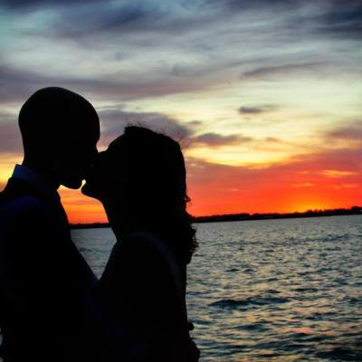 a man standing in front of a sunset over a body of water